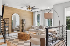 A modern living room with a sofa, coffee table, and a staircase with a railing. - Songbird A. Sleeps 12 . Comp Broadway Shuttle . Rooftop Jacuzzi (Nashville)