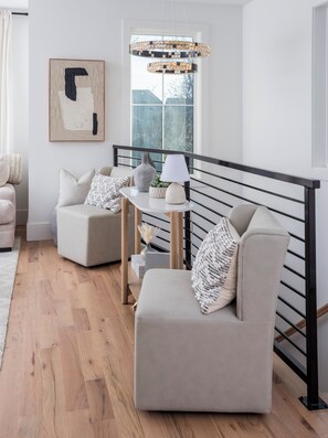Ein modernes Wohnzimmer mit zwei Sofas, einem kleinen Tisch mit Lampe, einer Dekorationsvase und einem gerahmten abstrakten Gemälde.
