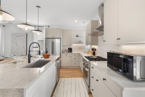 A modern kitchen with a central island, stainless steel appliances, and pendant lighting. - Songbird A. Sleeps 12 . Comp Broadway Shuttle . Rooftop Jacuzzi (Nashville)