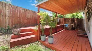 A wooden deck with a covered area, potted plants, and a wooden fence.