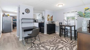 A compact kitchen with a dining area, a refrigerator, a microwave, and a dining table with chairs.