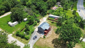 An aerial view of a residential area with a large house, a smaller building, and a road.