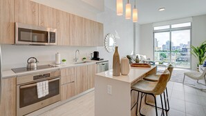 A modern kitchen with a microwave, oven, sink, and bar area. - AEA - Biscayne BLVD Miami (Miami)