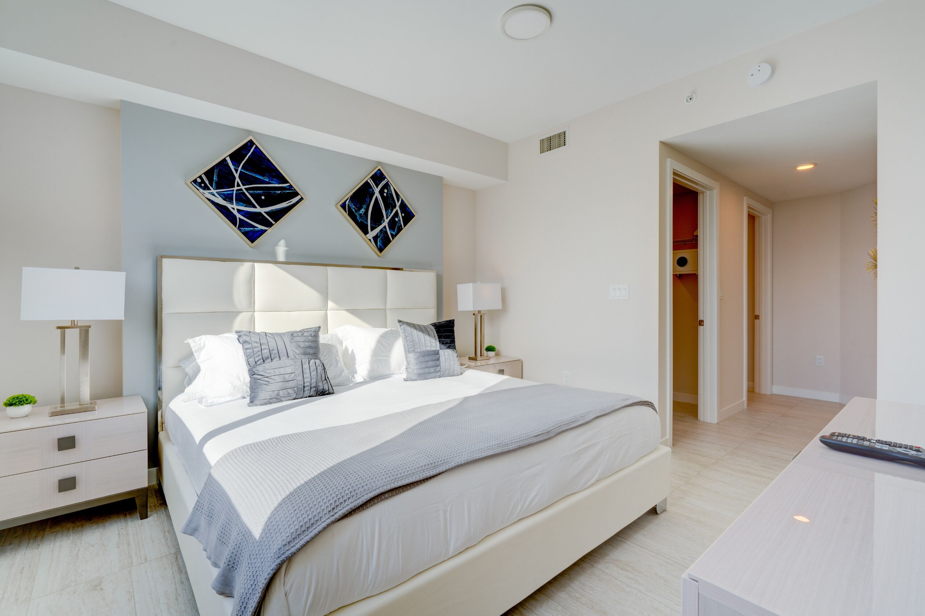 Ein modernes Schlafzimmer mit einem großen Bett, Nachttischen und abstrakter Wandkunst.