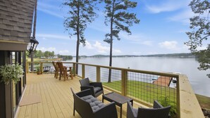 Eine Terrasse mit Gartenmöbeln, die auf einen See blickt, mit Geländer und Blick auf das Wasser.