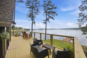Una terraza con mobiliario exterior que da a un lago, una barandilla y vistas al agua.