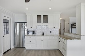 Una cocina moderna con muebles blancos, electrodomésticos de acero inoxidable y encimera de granito.