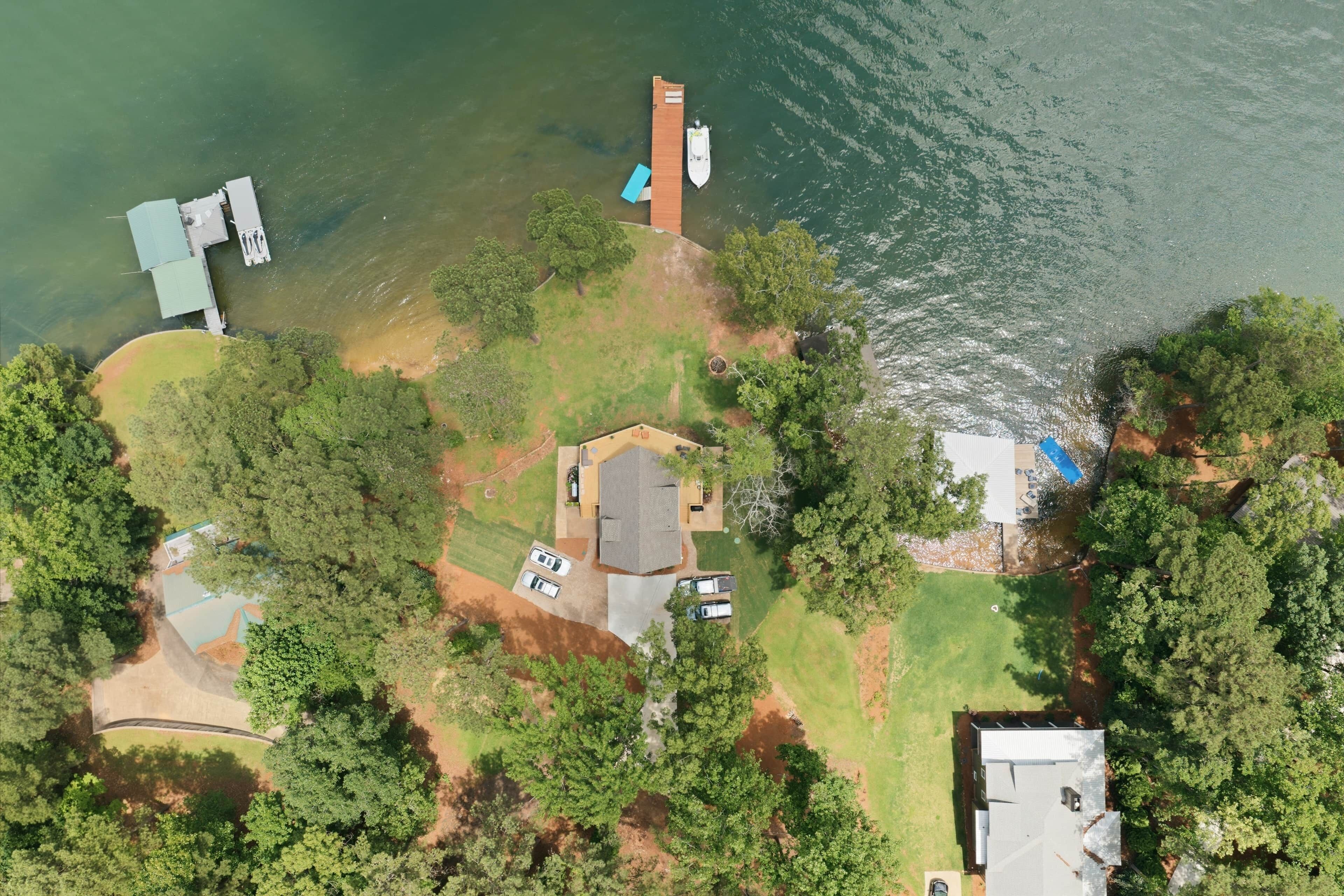 An aerial view of a residential area with a dock, a house, and a boat.