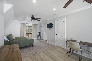 Une chambre à coucher comprenant un lit, un bureau, une chaise, un ventilateur de plafond et un téléviseur.