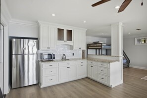 A modern kitchen with white cabinetry, a stainless steel refrigerator, a microwave, and a built-in oven. - Brighter Days-Lake Martin Retreat (Tallapoosa County)