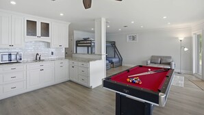 Eine moderne Küche mit weißen Schränken, einem Billardtisch und einem Deckenventilator.
