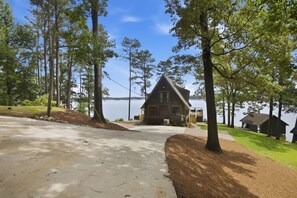 A cabin with a sloped roof, surrounded by trees and a lake. - Brighter Days-Lake Martin Retreat (Tallapoosa County)
