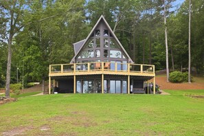 A large, modern house with a prominent triangular roof, multiple windows, and a covered porch area. - Brighter Days-Lake Martin Retreat (Tallapoosa County)