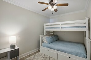 A bunk bed with a ceiling fan, a bedside table with a lamp, and a white nightstand. - Brighter Days-Lake Martin Retreat (Tallapoosa County)