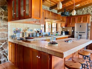 A spacious kitchen with wooden cabinets, a large island, and bar stools.