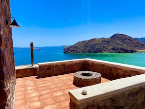A balcony with a view of a coastal landscape, a cactus, and a stone lantern.
