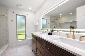 A modern bathroom with a large mirror, dual sinks, and a shower. - Wake & Lake Lodge, Private Dock, Deep Water & Incredible Lake Views (Graford)