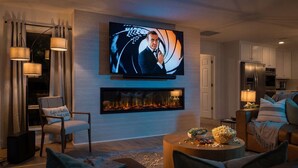 A modern living room with a flat-screen TV, a fireplace, a sofa, and a dining area.