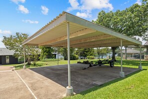 A covered outdoor area with a concrete floor, a metal roof, and a trailer parked inside. - Wake & Lake Lodge, Private Dock, Deep Water & Incredible Lake Views (Graford)