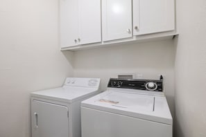 A laundry area with two washing machines and a cabinet above. - Wake & Lake Lodge, Private Dock, Deep Water & Incredible Lake Views (Graford)
