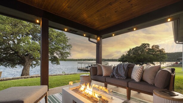 An outdoor seating area with a fire feature, a sofa, and a view of a lake.