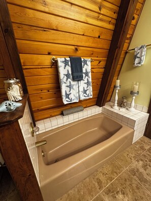 A bathroom with a wooden wall, a bathtub, a towel rack, and a mirror. - Chalet Getaway in Beautiful Show Low Arizona (Show Low)
