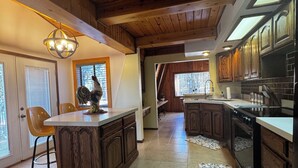 Una cocina con armarios de madera, una isla central y un ventanal grande.