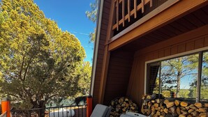 Una terraza de madera con dos sillones de descanso y una pila de leña.