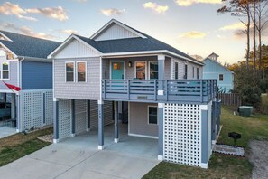 Ein zweistöckiges Haus mit Balkon, Garage und einer kleinen Veranda.