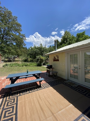 A patio with a picnic table, a grill, and a covered area with a door. - Lazy Lake Outpost (Kettle Falls)