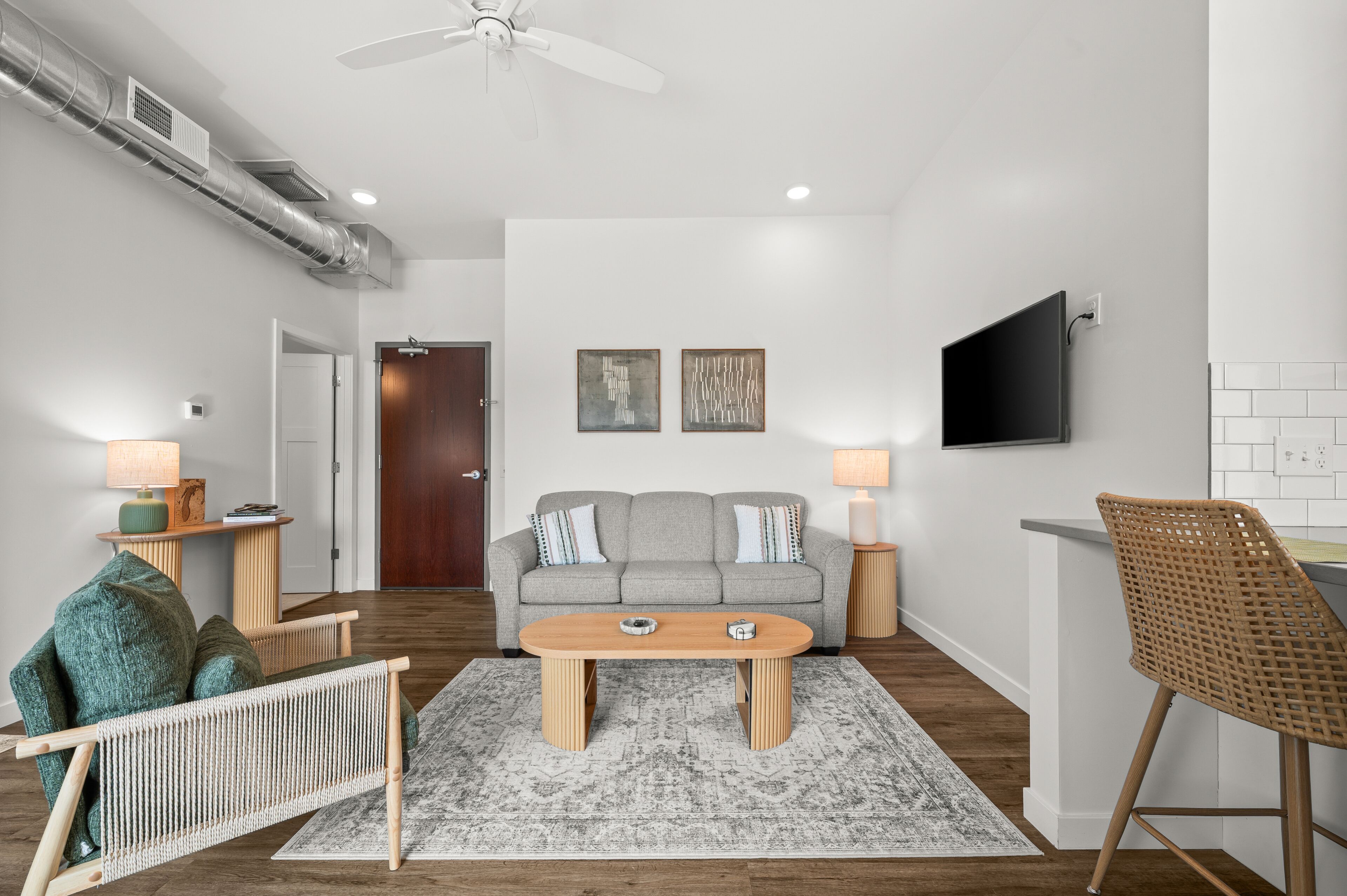 A modern living room with a sofa, coffee table, and a TV mounted on the wall.