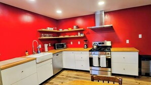 A kitchen with red walls, white cabinets, a wooden countertop, a stove, a microwave, and a sink.