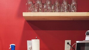 A kitchen with a dishwasher, a microwave, a wooden countertop, and a red wall.