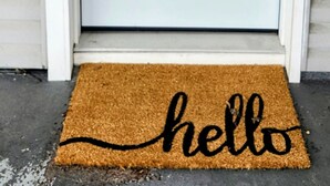 A white door with a small window, a doorbell, and a doormat with 'hello' written on it.