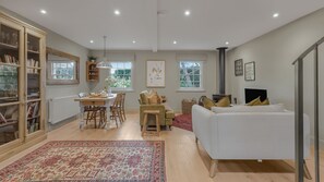 Ein geräumiger Wohnbereich mit Esstisch, Sofa und Bücherregal.