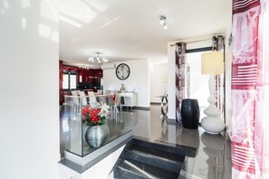 Eine moderne Hotelhalle mit Glastrennwand, einer Uhr, einem Essbereich und einer Treppe.