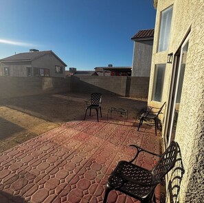 Eine Terrasse mit Backsteinboden, zwei Metallstühlen und einem kleinen Tisch.