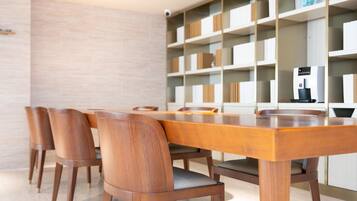 A dining area with a wooden table and chairs, a coffee machine, and a bookshelf with various items.