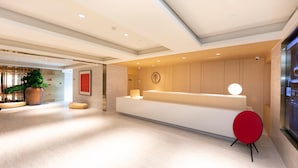 A modern reception area with a reception desk, a potted plant, and a digital display. - Ji Hotel (Nanjing)