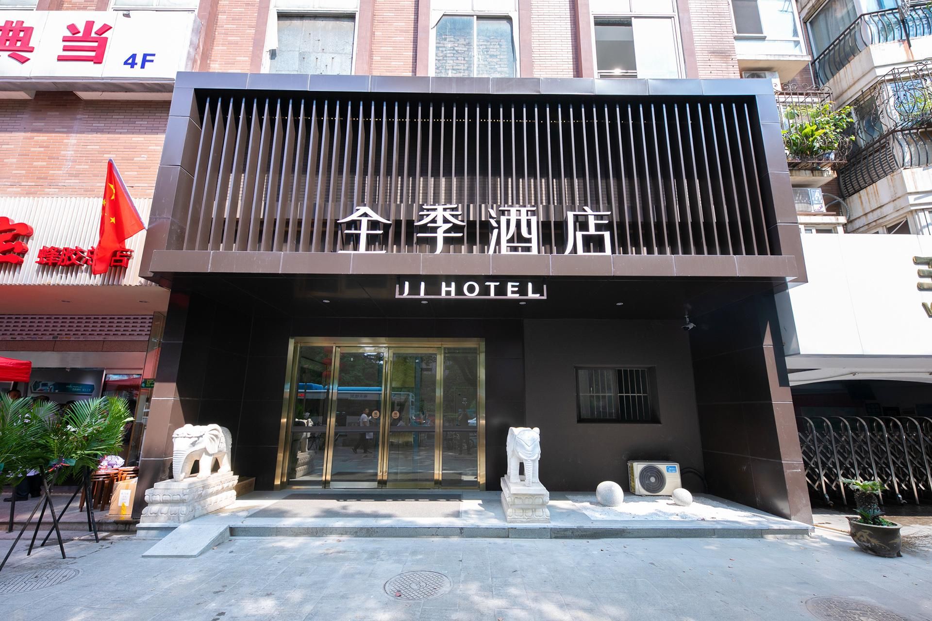 A hotel entrance with a modern facade, a lion statue, and a flag.