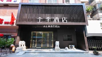 A hotel entrance with a modern facade, a lion statue, and a flag.