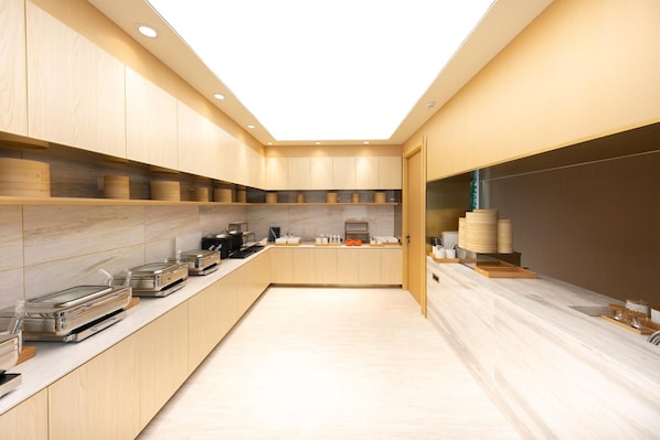 A modern kitchen with wooden cabinets, a marble countertop, and various kitchen appliances. - Ji Hotel (Nanjing)