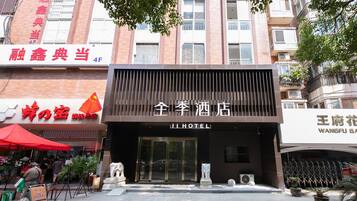 A hotel entrance with a modern facade, a large glass door, and a sign indicating the name 'JI HOTEL'.