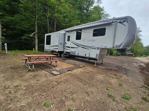 A recreational vehicle with a picnic table and a covered area. - Cozy RV Rental at Sleepy Hollow Campgrounds (Gaines)
