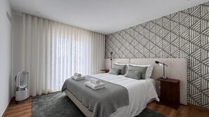 A modern bedroom with a bed, bedside tables, a lamp, and a patterned wall. - GuestReady - Charming retreat in Fátima (Fátima)