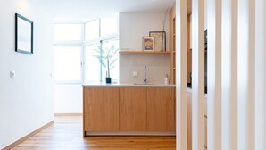 A modern kitchen with wooden cabinets, a countertop, and a window providing natural light. - GuestReady - Charming retreat in Fátima (Fátima)
