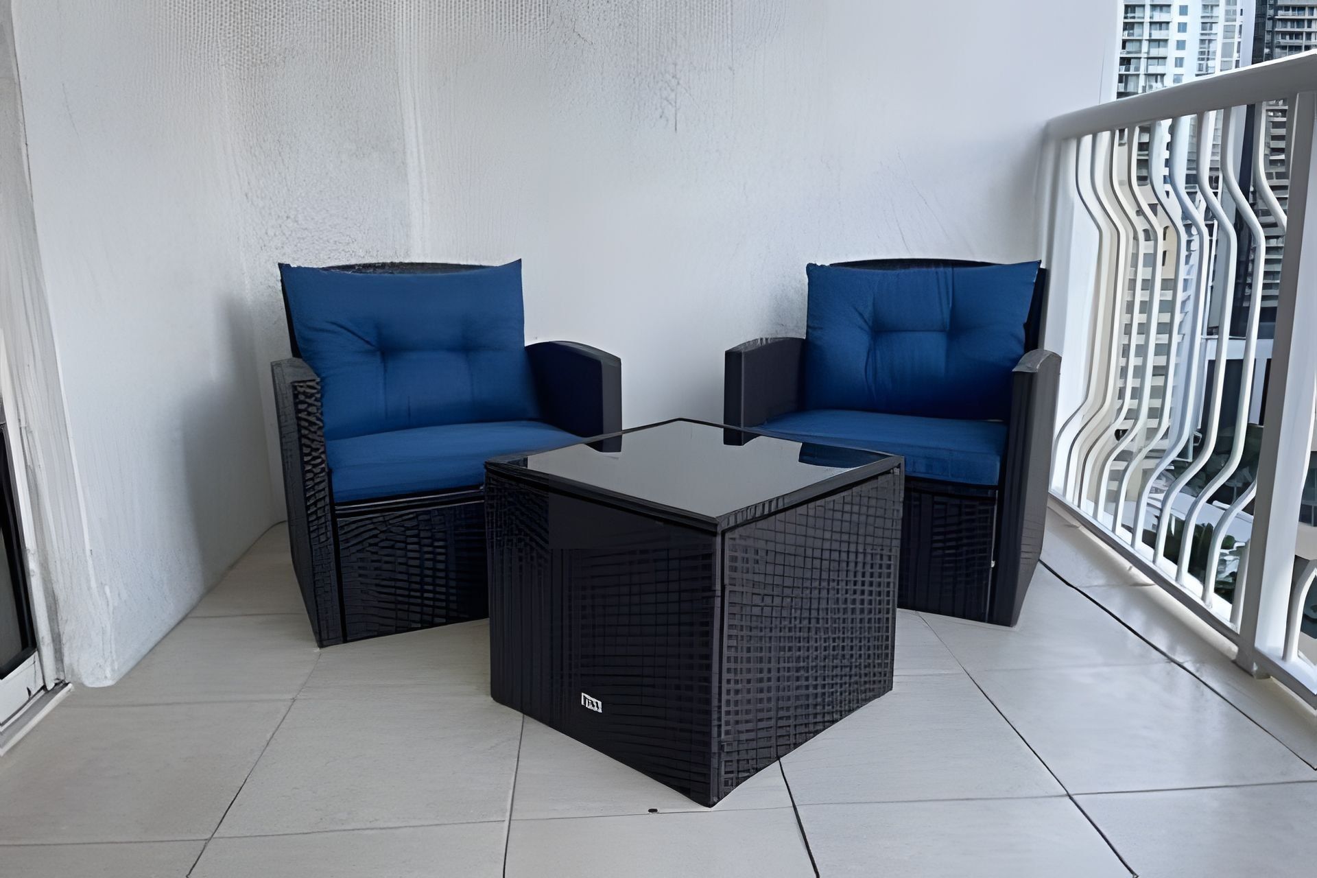 A balcony with two blue cushioned chairs and a black square table.