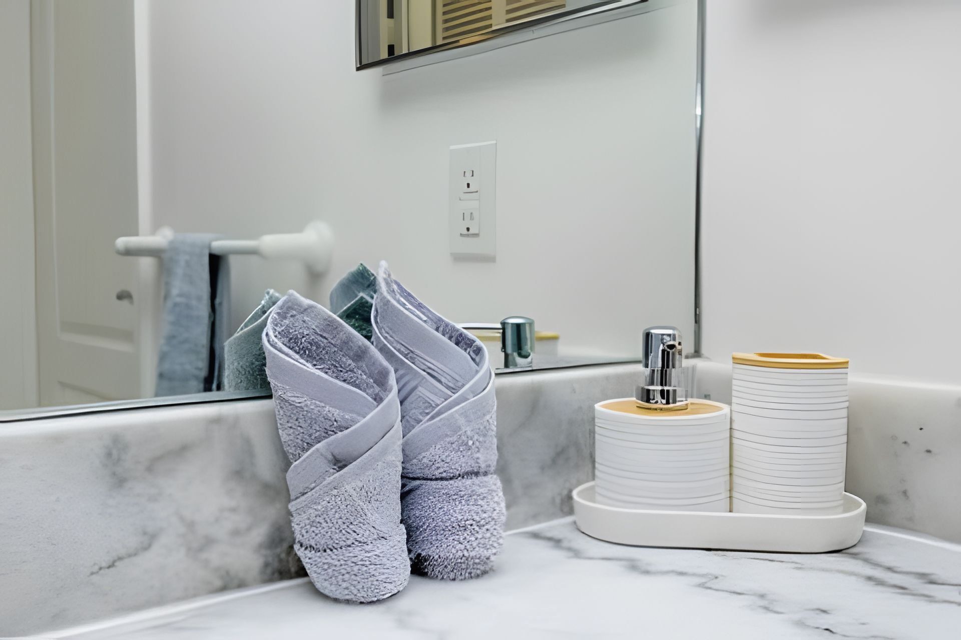 Une salle de bain avec un comptoir en marbre, un porte-serviettes, un miroir et un lavabo.