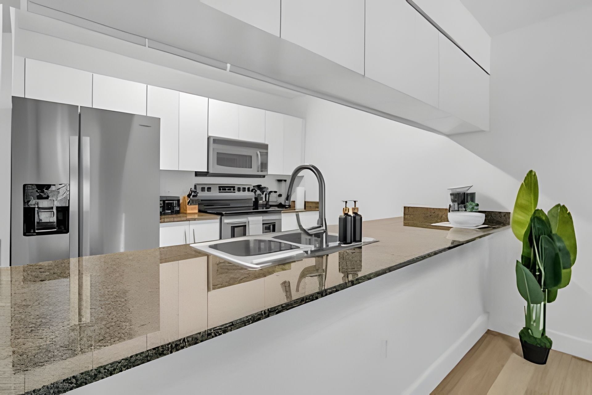 A modern kitchen with white cabinets, stainless steel appliances, and a granite countertop.