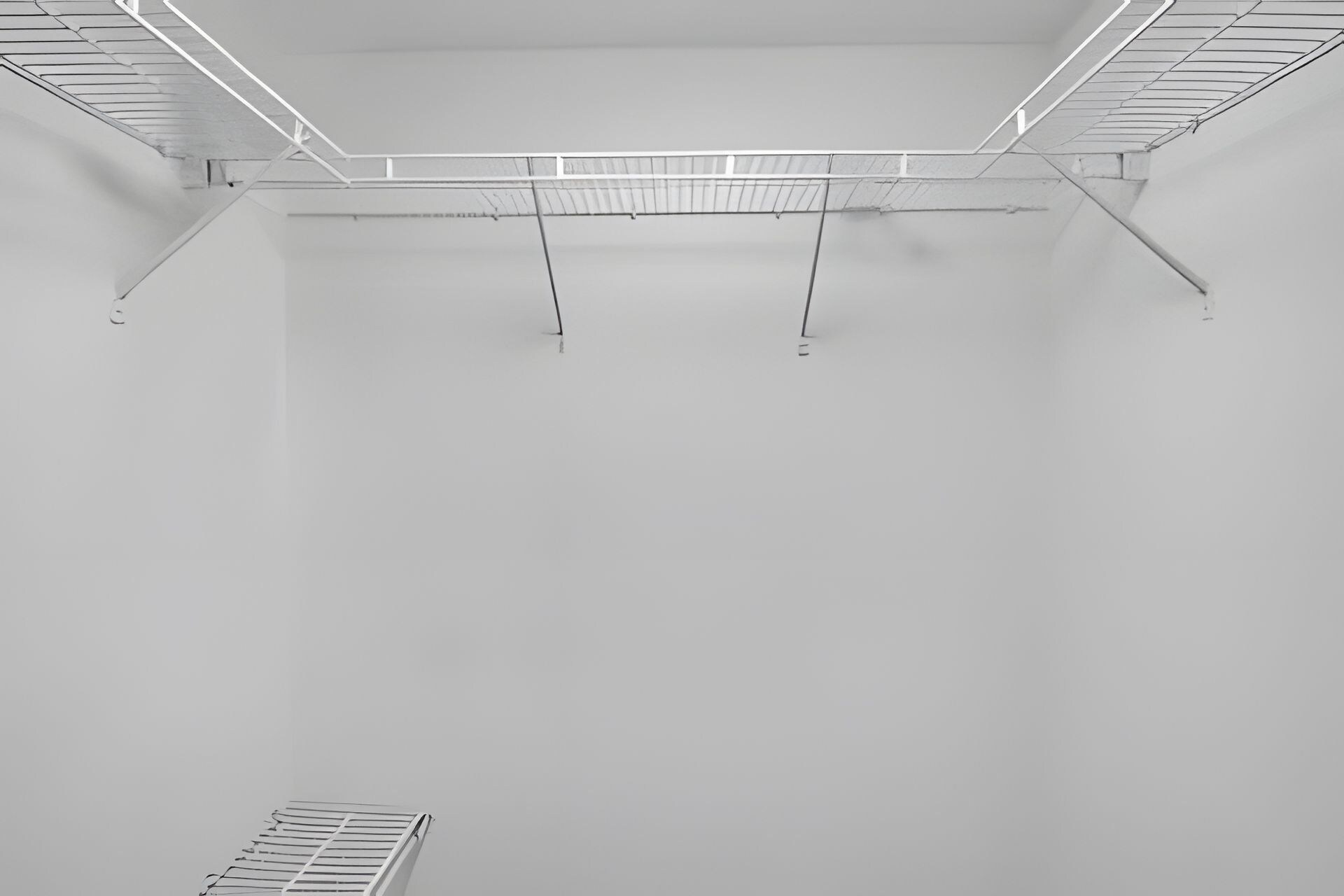 A room with a white ceiling, metal beams, and a metal rack.